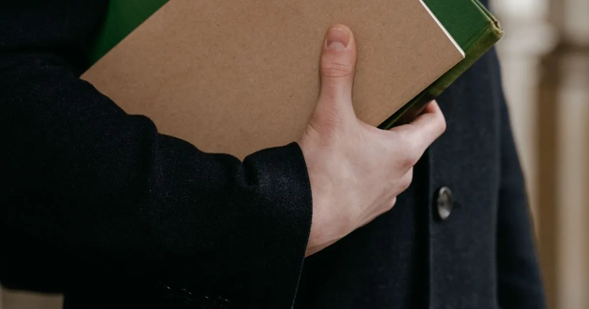 Manos sosteniendo una carpeta con documentos antes de entregarla
