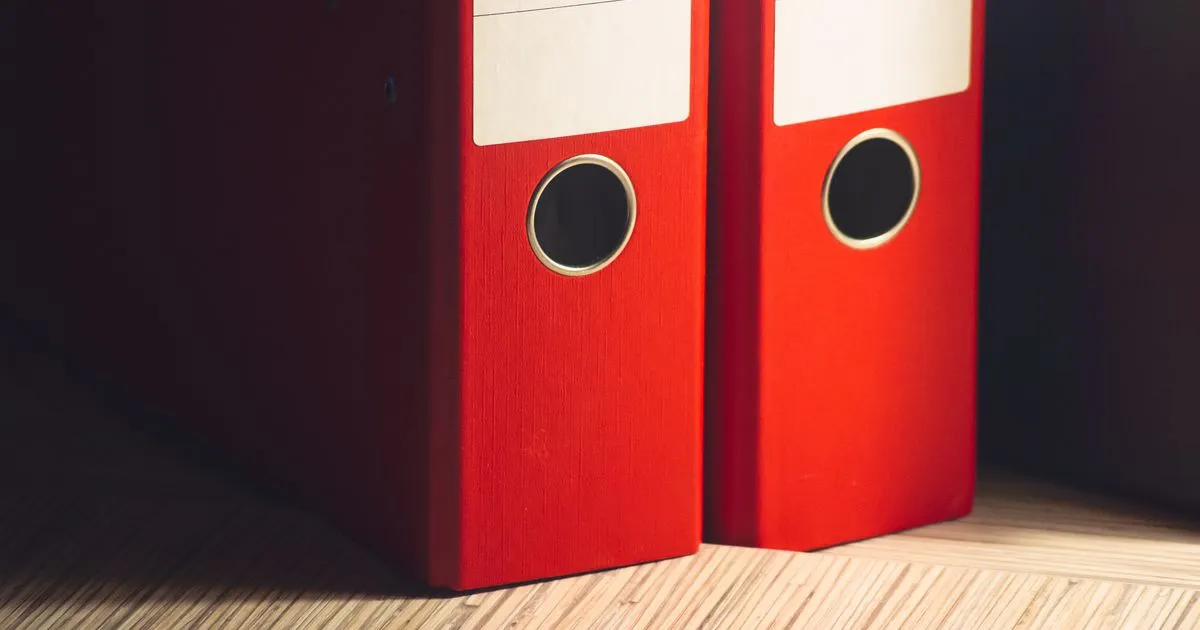 Dos archivadores rojos con las etiquetas en blanco sobre un escritorio de madera