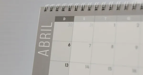 Calendario de escritorio con espiral abierto en la hoja de abril, con los días en primer plano