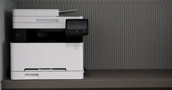 Impresora multifuncional apagada sobre un mueble de oficina