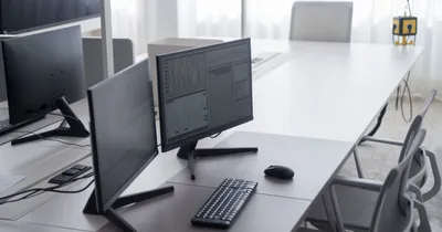 Puesto de trabajo de oficina con dos monitores y teclado, junto a una ventana
