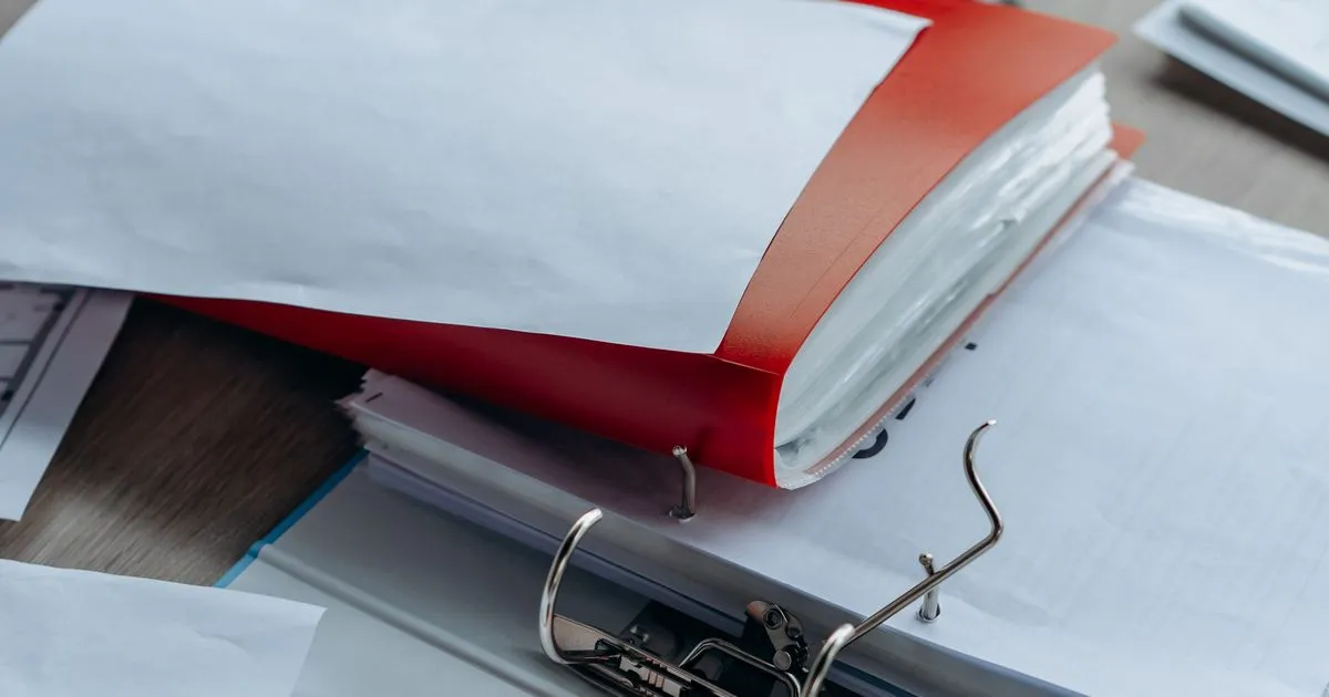Archivador de anillas rojo abierto sobre un escritorio, con documentos ordenados