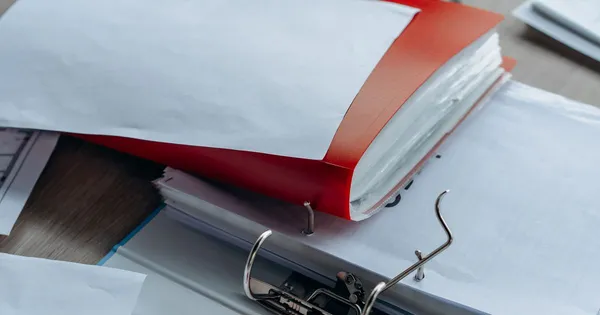 Archivador de anillas rojo abierto sobre un escritorio, con documentos ordenados
